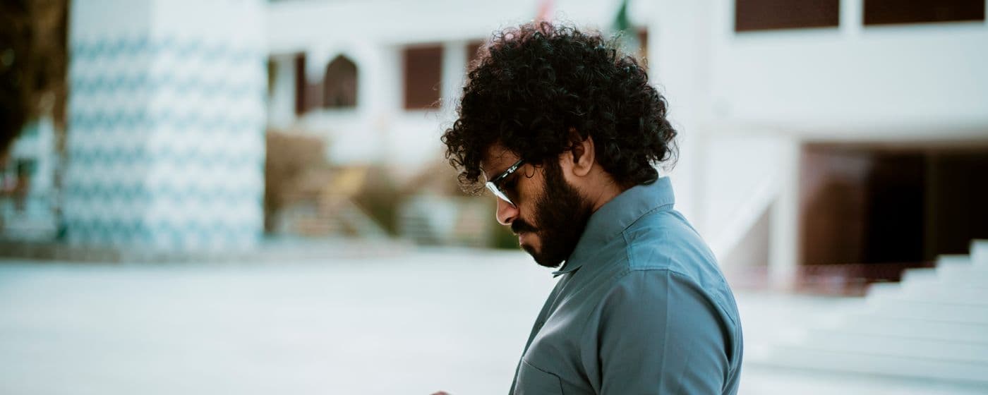 Une personne consulte son téléphone, à l’extérieur d’un bâtiment