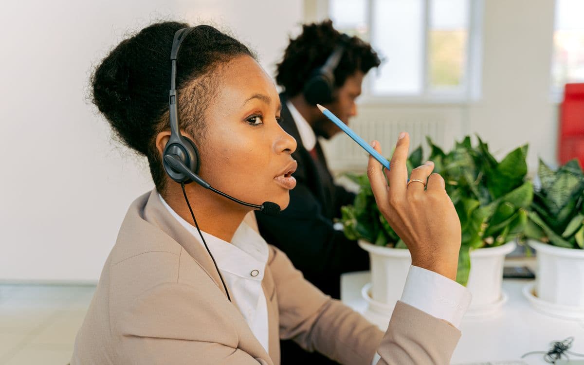 Deux conseillers équipés d’un casque, en conversation depuis leur bureau